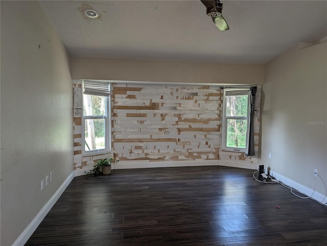 unfurnished room featuring dark hardwood / wood-style floors, a healthy amount of sunlight, and a textured ceiling