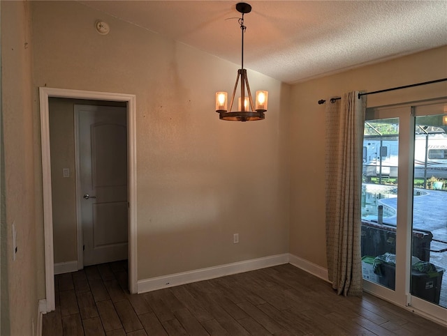 unfurnished room with a textured ceiling, dark hardwood / wood-style flooring, and an inviting chandelier