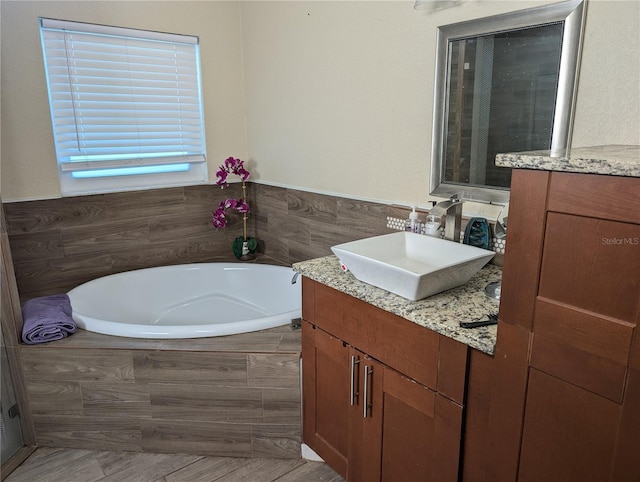 bathroom featuring vanity and tiled tub