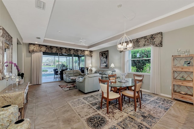 dining room with ornamental molding, ceiling fan with notable chandelier, and a raised ceiling