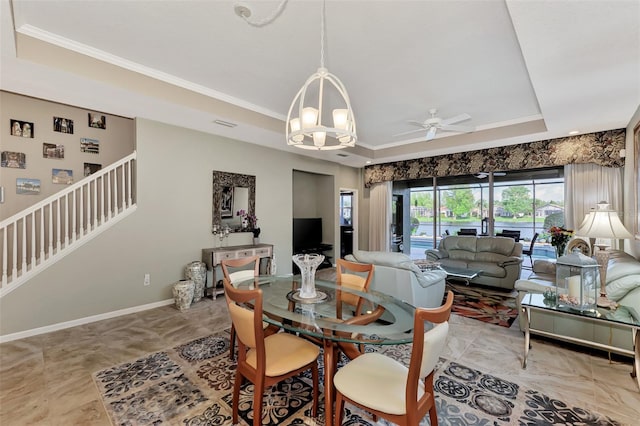 dining area featuring ceiling fan with notable chandelier, crown molding, and a raised ceiling