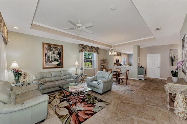 living room with a tray ceiling and ceiling fan with notable chandelier