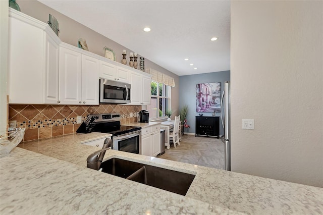 kitchen featuring white cabinets, sink, backsplash, and appliances with stainless steel finishes