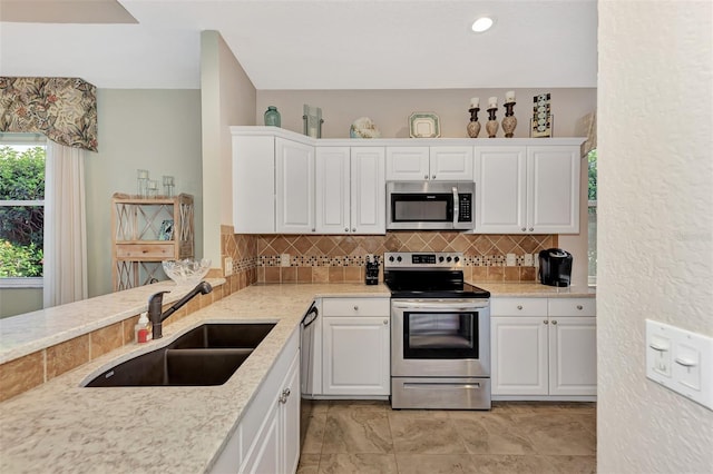 kitchen with stainless steel appliances, white cabinetry, sink, and decorative backsplash