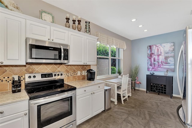 kitchen with tasteful backsplash, light stone countertops, white cabinets, and stainless steel appliances