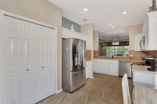 kitchen with decorative backsplash, hanging light fixtures, a textured ceiling, white cabinetry, and appliances with stainless steel finishes