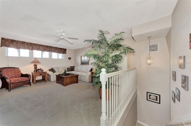 carpeted living room featuring ceiling fan and a textured ceiling