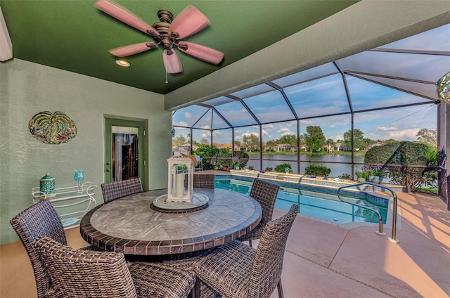 view of swimming pool featuring a water view, glass enclosure, ceiling fan, and a patio area