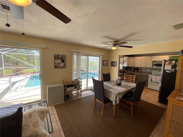 dining space with a textured ceiling, a healthy amount of sunlight, and light tile patterned flooring