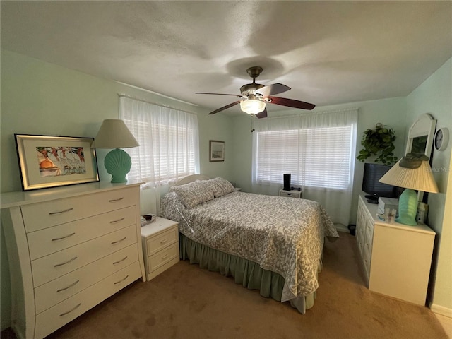 carpeted bedroom featuring multiple windows and ceiling fan