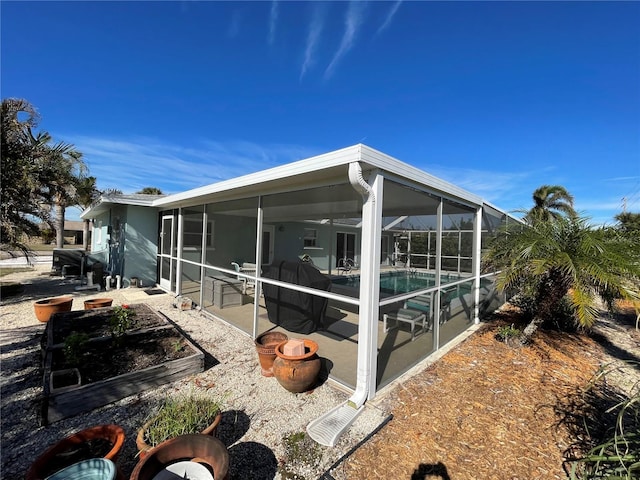 view of property exterior with a sunroom, glass enclosure, a patio area, and a swimming pool