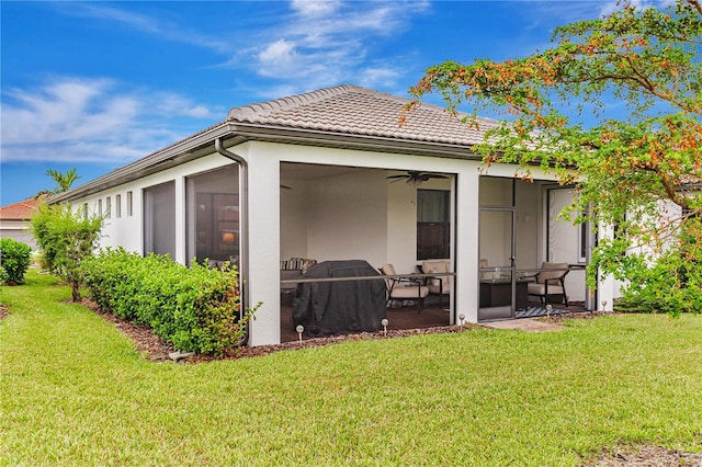 back of property with a sunroom, ceiling fan, and a yard