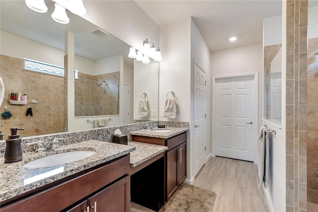 bathroom with hardwood / wood-style floors, vanity, and a tile shower