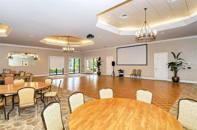 dining room with a tray ceiling, crown molding, light parquet flooring, and a chandelier