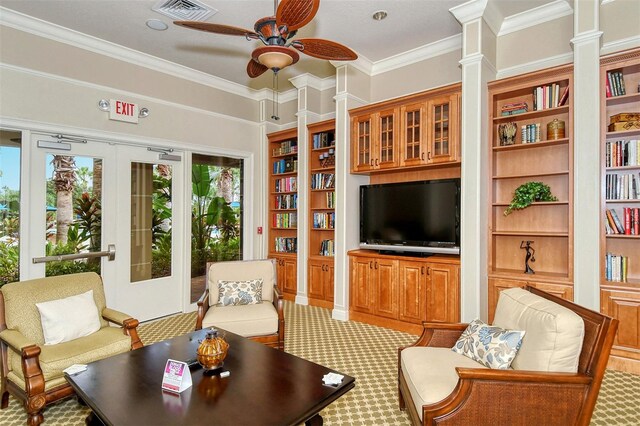 carpeted living room featuring french doors, ornate columns, ornamental molding, built in shelves, and ceiling fan