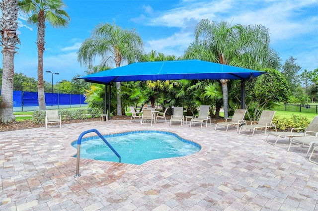 view of pool featuring a water view, a patio area, and tennis court