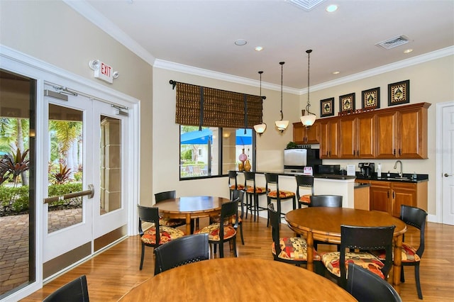 dining space featuring sink, dark wood-type flooring, french doors, and ornamental molding