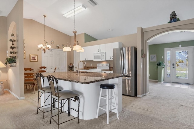 kitchen with light carpet, a kitchen breakfast bar, white cabinets, dark stone countertops, and white appliances