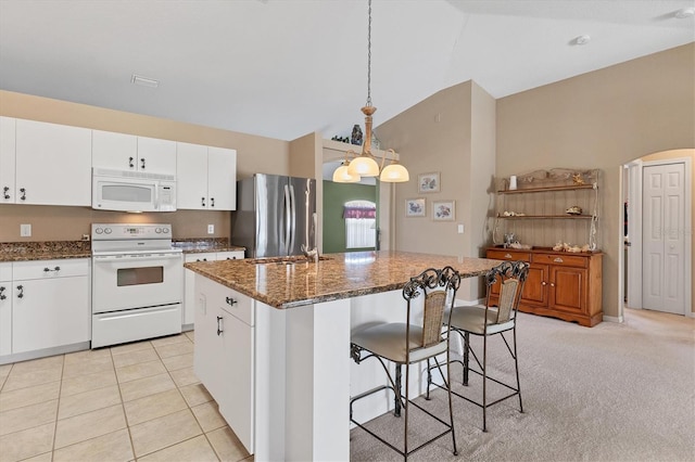 kitchen featuring pendant lighting, light colored carpet, white appliances, and an island with sink