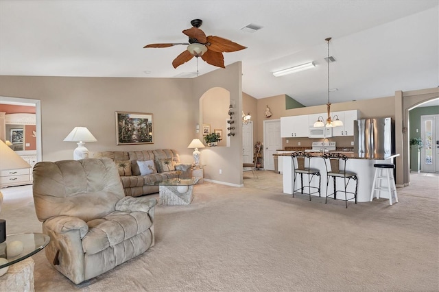 carpeted living room with ceiling fan and vaulted ceiling