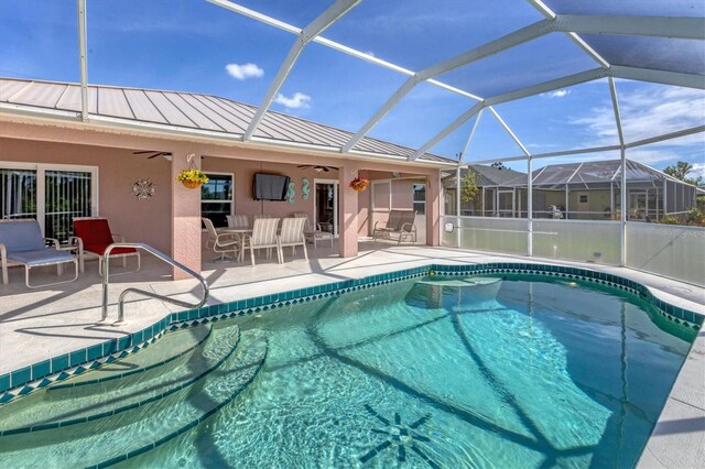 view of pool featuring glass enclosure, a patio area, and ceiling fan