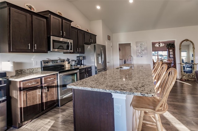 kitchen featuring stainless steel appliances, lofted ceiling, hardwood / wood-style flooring, an island with sink, and dark brown cabinets