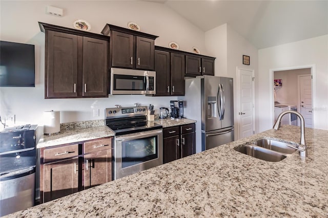 kitchen featuring lofted ceiling, dark brown cabinetry, sink, appliances with stainless steel finishes, and washer / clothes dryer