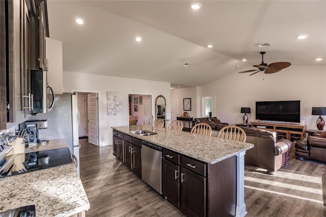 kitchen featuring dark hardwood / wood-style flooring, stainless steel appliances, lofted ceiling, a center island with sink, and light stone countertops