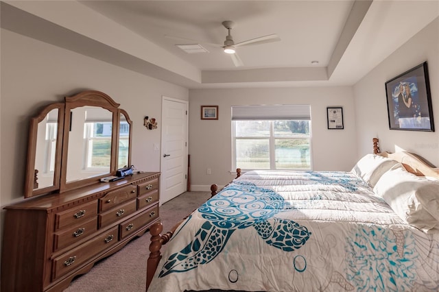 bedroom featuring ceiling fan, carpet floors, and a tray ceiling