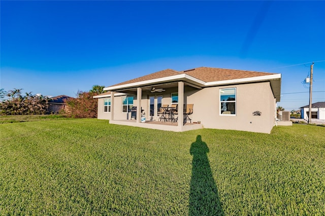 rear view of property featuring a lawn, ceiling fan, and a patio area