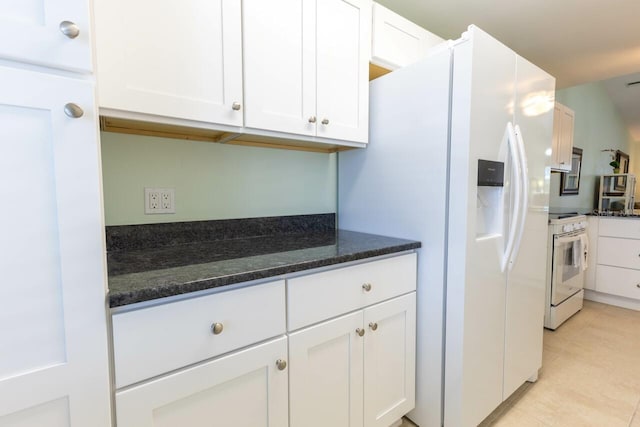 kitchen with white cabinetry, white appliances, dark stone counters, and light tile patterned flooring