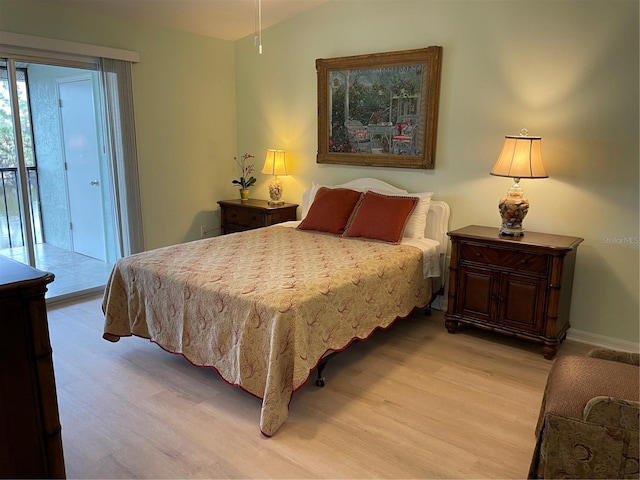 bedroom featuring access to exterior, vaulted ceiling, and light wood-type flooring