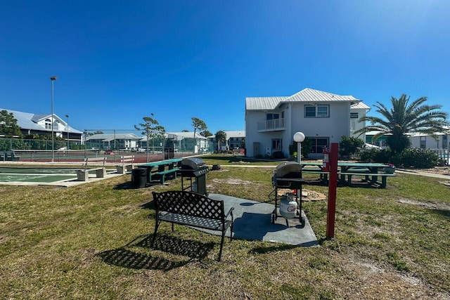 view of community featuring tennis court and a lawn