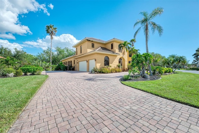 mediterranean / spanish-style home with a garage and a front lawn