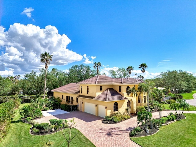 mediterranean / spanish house with a garage and a front lawn