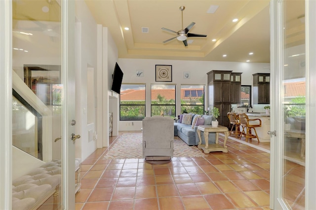 living room with light tile patterned floors, french doors, a tray ceiling, and ceiling fan