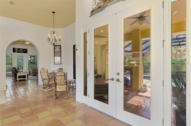 doorway to outside with tile patterned floors, ceiling fan with notable chandelier, and french doors