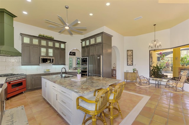 kitchen featuring an island with sink, tasteful backsplash, light stone counters, white cabinetry, and stainless steel appliances