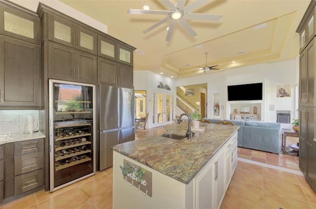 kitchen featuring backsplash, dark stone countertops, sink, and a tray ceiling