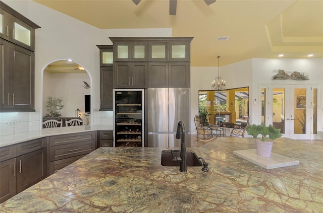 kitchen featuring light stone counters, dark brown cabinetry, french doors, and tasteful backsplash