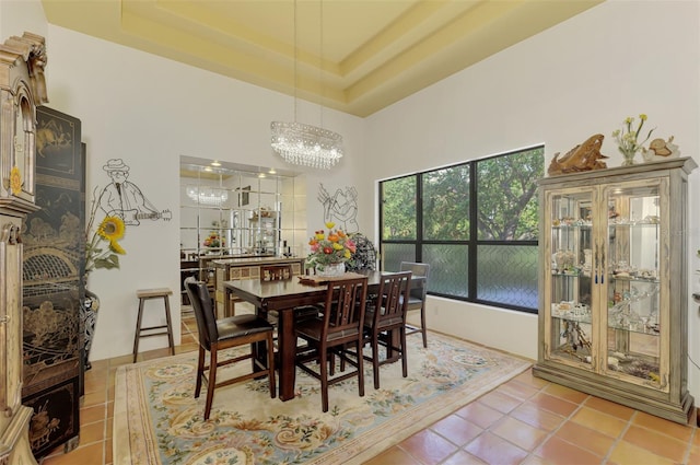 tiled dining room featuring a chandelier and a tray ceiling