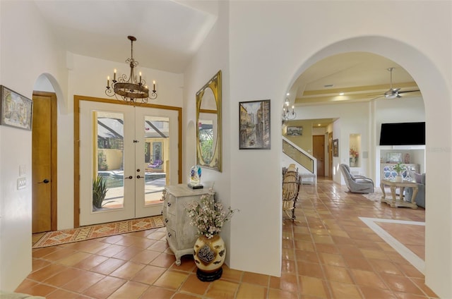 foyer featuring tile patterned floors, french doors, and ceiling fan with notable chandelier