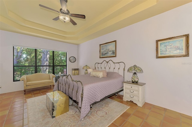 bedroom with a raised ceiling, ceiling fan, and light tile patterned flooring