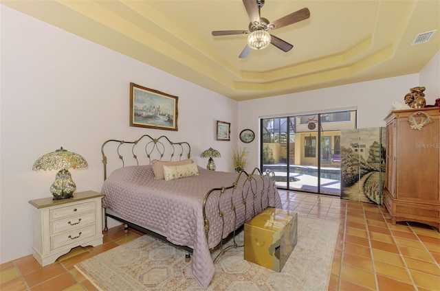 tiled bedroom featuring ceiling fan, access to exterior, and a tray ceiling