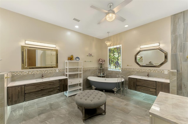 bathroom with vanity, ceiling fan, tile walls, and a washtub