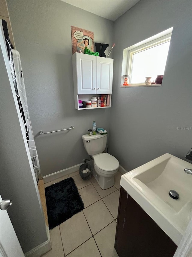 bathroom with toilet, vanity, and tile patterned floors