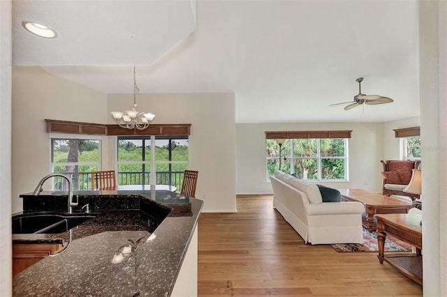 kitchen with pendant lighting, light hardwood / wood-style floors, plenty of natural light, and dark stone counters