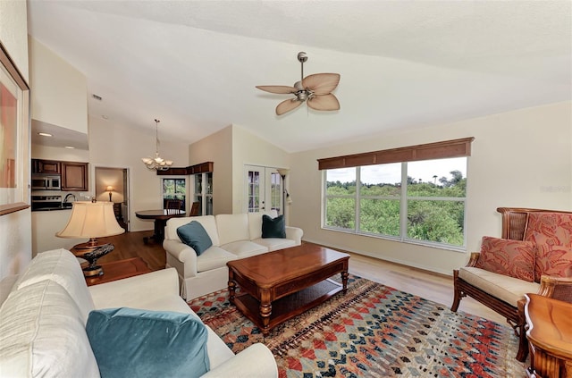 living room featuring light hardwood / wood-style floors, ceiling fan with notable chandelier, and lofted ceiling