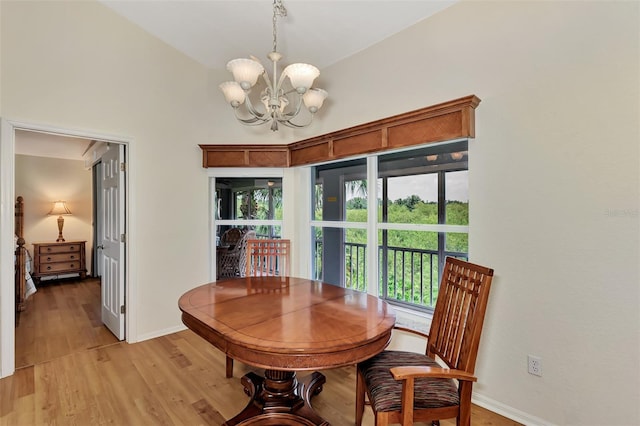 dining space featuring vaulted ceiling, a notable chandelier, and light hardwood / wood-style flooring