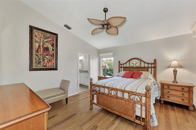 bedroom featuring ceiling fan, connected bathroom, light wood-type flooring, and vaulted ceiling